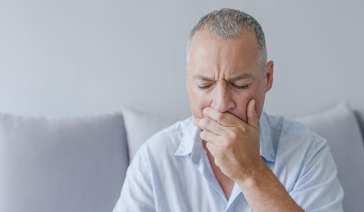 Man holds his hand in front of his mouth The causes of an aphtae have not yet been clarified